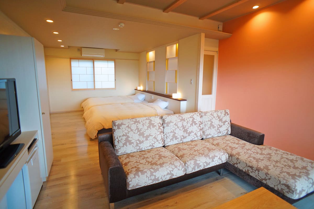 A modern hotel room with a sofa, a bed, and a TV.