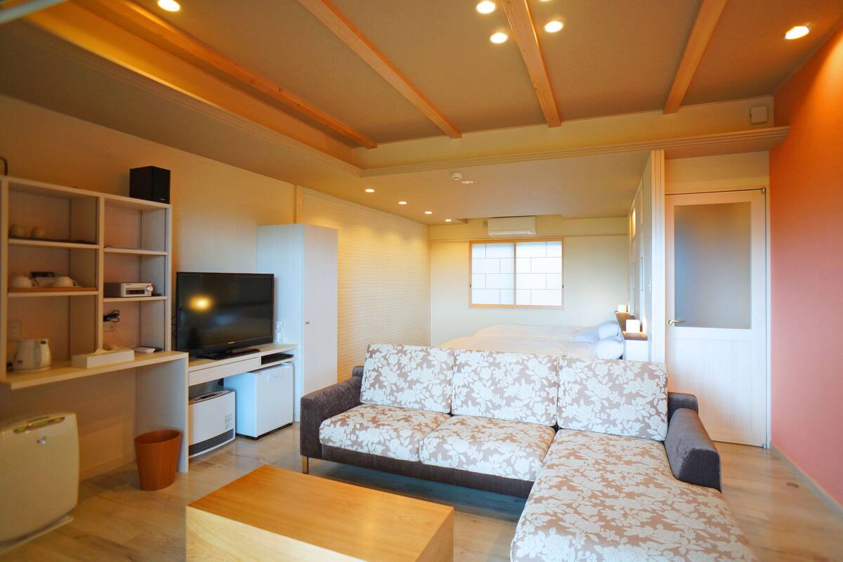 A modern living room with a sectional sofa, a flat-screen TV, a coffee table, and built-in shelving.