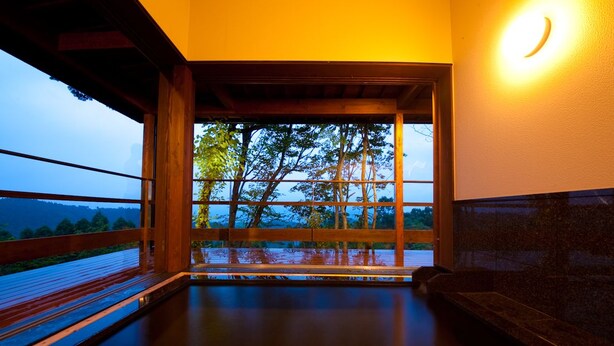 A room with a large window, wooden floor, and a wall-mounted light fixture.
