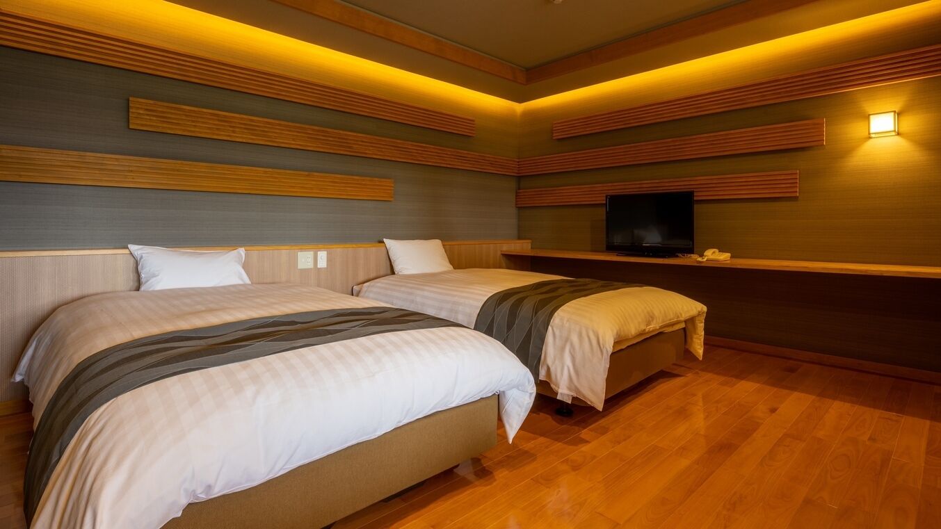 Ein Hotelzimmer mit zwei Betten, einem Flachbildfernseher und Holzwandverkleidung.