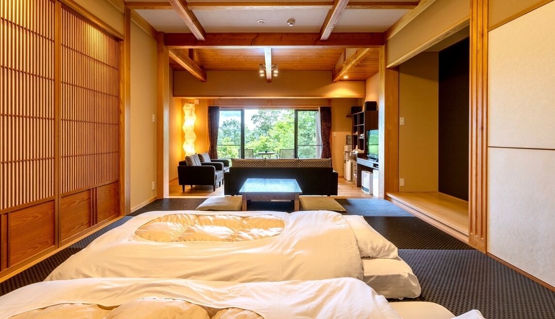Ein Zimmer mit einem Bett, einer Couch, einer Massageliege und Blick ins Freie.