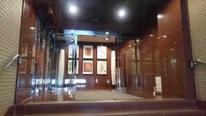 Eine moderne Lobby mit Glastür, gefliesten Wänden und einer zentralen Treppe.