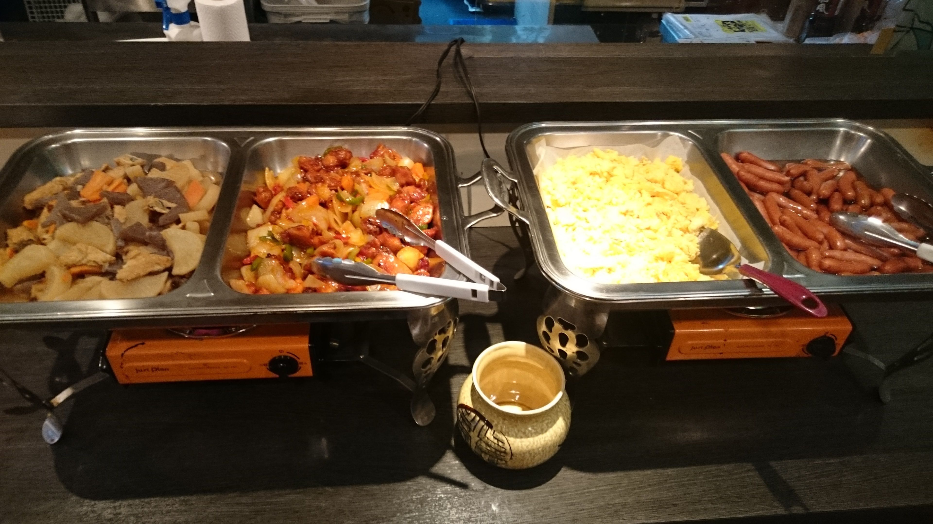 Buffet com diversos pratos, incluindo carnes, legumes e arroz.