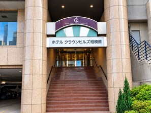 A hotel entrance with a sign indicating 'Hotel Crown Hills Saginomiya' and a staircase leading to the lobby.
