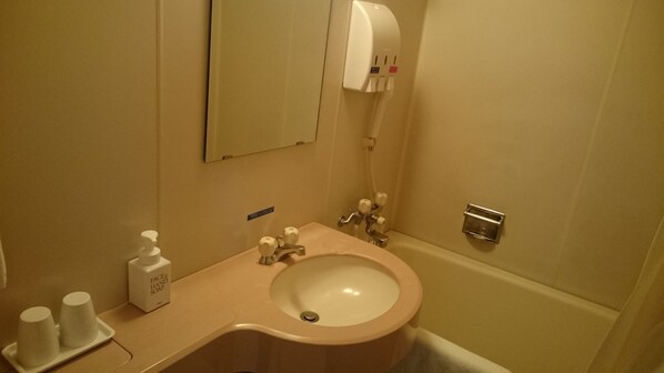 A bathroom with a sink, a mirror, a soap dispenser, and a towel rack. - Hotel Crown Hills Sagamihara (Sagamihara)