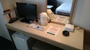 A hotel room desk with a computer monitor, a coffee maker, a tray with glasses, a tissue box, and a menu. - Hotel Crown Hills Sagamihara (Sagamihara)