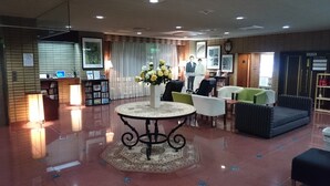 Eine Lobby mit einer Rezeption, einer Sitzecke und einer Wand mit gerahmten Bildern.