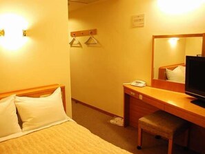 Ein Hotelzimmer mit Bett, Schreibtisch mit Telefon, Stuhl und Fernseher.