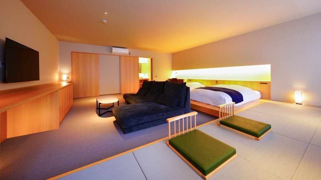 Une chambre d’hôtel moderne équipée d’un canapé, d’un lit, d’une télévision et d’une petite table.