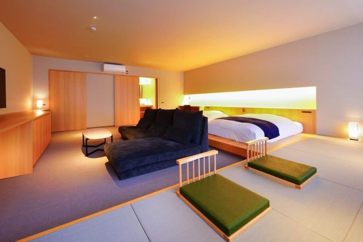 Une chambre d’hôtel moderne équipée d’un canapé, d’un lit, d’une télévision et d’une petite table.