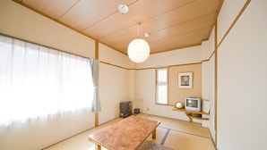 A traditional Japanese room with tatami flooring, a low wooden table, a hanging paper lantern, and a television on a shelf. - Alpine Inn Mizushiro (Matsumoto)