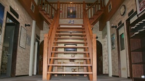 A wooden staircase leading to an upper floor, flanked by stone walls and wooden doors. - Alpine Inn Mizushiro (Matsumoto)