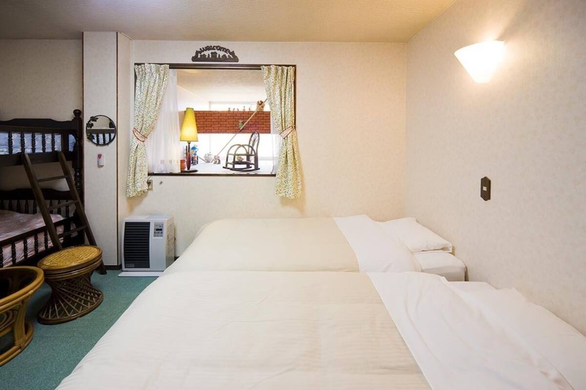 Habitació amb lliteres, un llit individual, un mirall amb cortines, una làmpada i un calefactor.