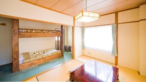 A traditional Japanese room with tatami flooring, a low wooden bed, a wooden table, and a sliding door. - Alpine Inn Mizushiro (Matsumoto)