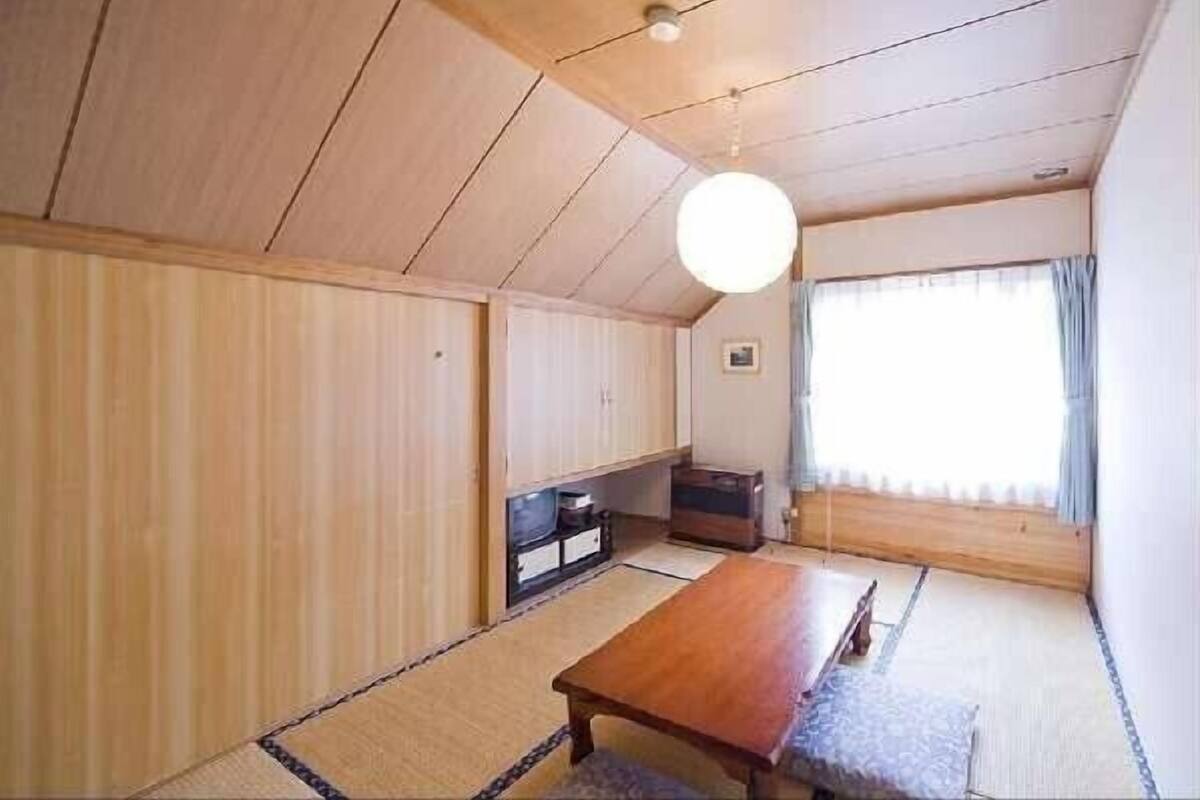 Una habitació tradicional japonesa amb fons de tatami, una taula de fusta baixa i portes corredisses.