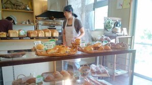 A bakery display case with various baked goods and a person in the background. - Yugafu Kabira Ishigaki (Ishigaki)