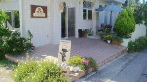 A building with a tiled exterior, a signboard, and a small outdoor seating area with plants and an umbrella. - Yugafu Kabira Ishigaki (Ishigaki)