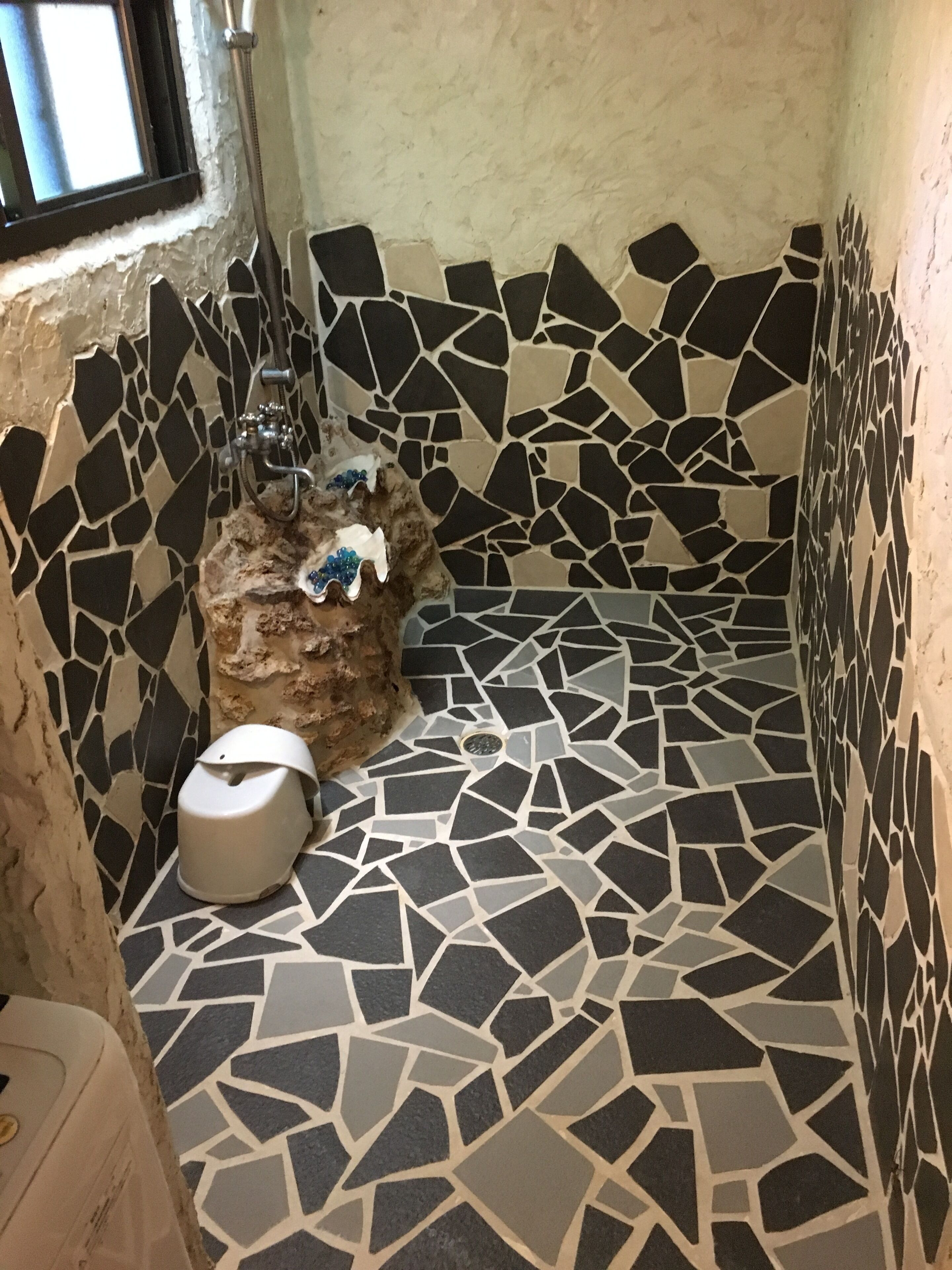 Ett badrum med ett mosaikgolv, en toalett och en duschhörna.