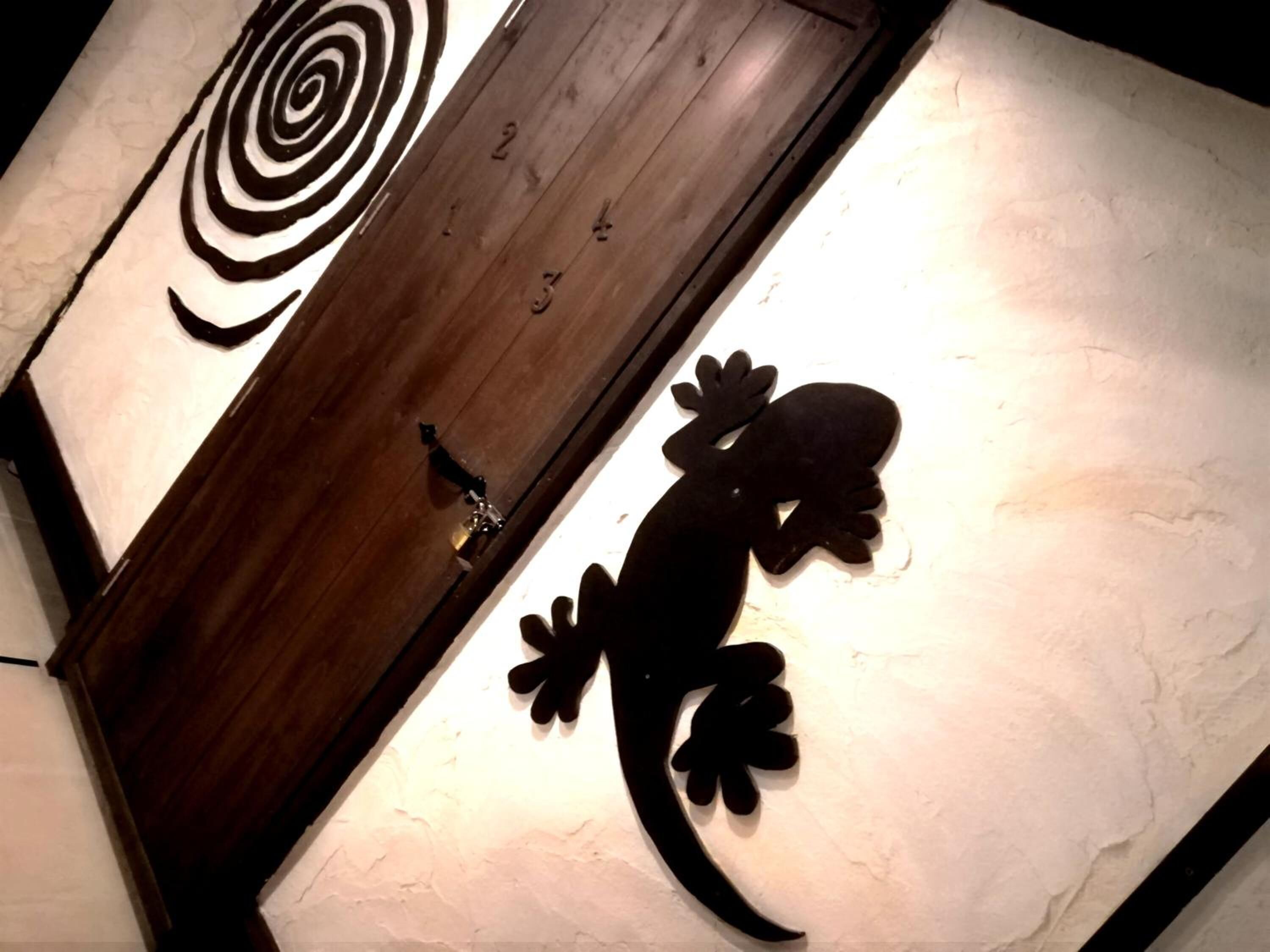 A wall with a wooden panel and a lizard cutout.