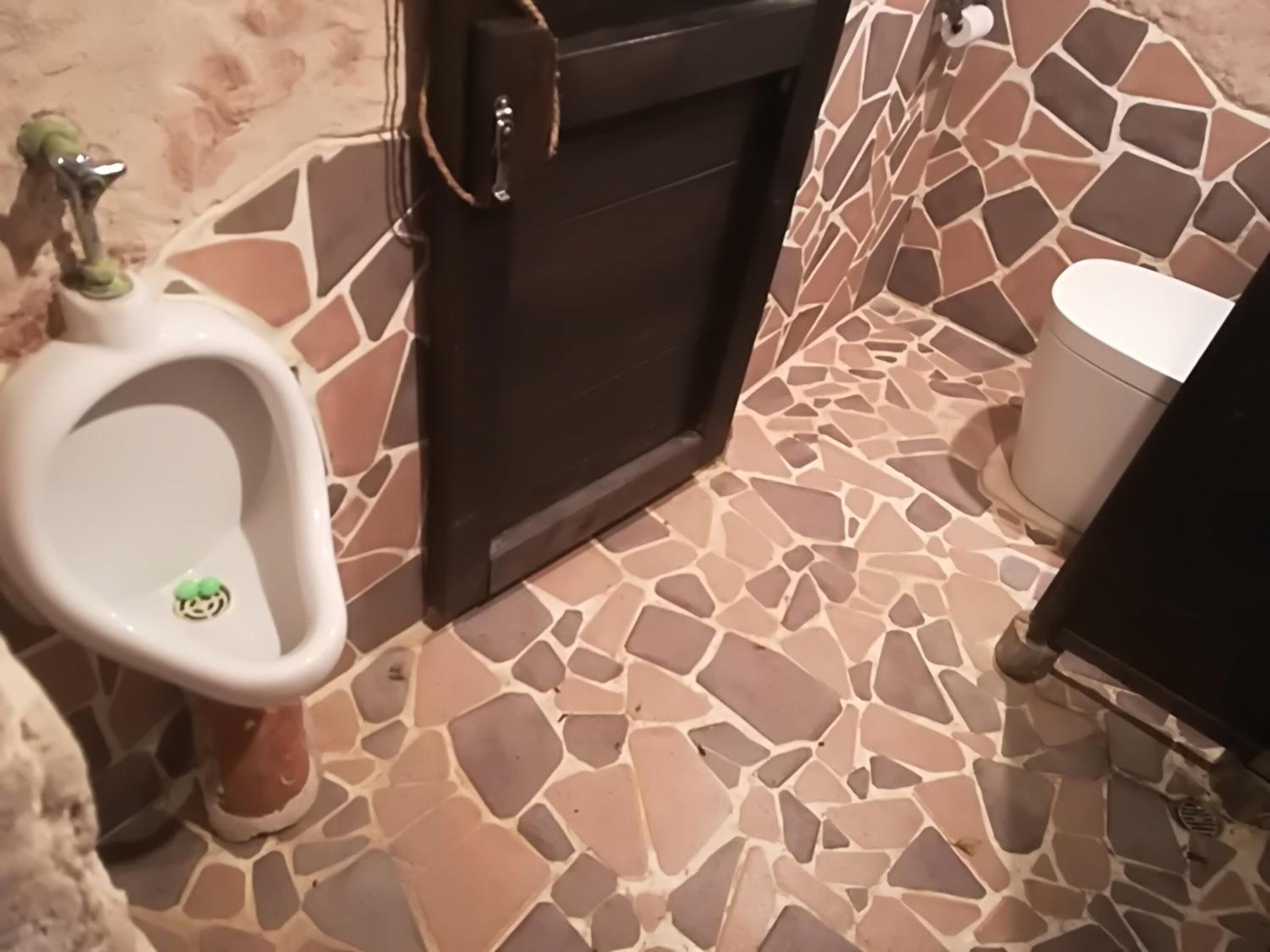 Un baño con un orinal, un inodoro y una puerta.