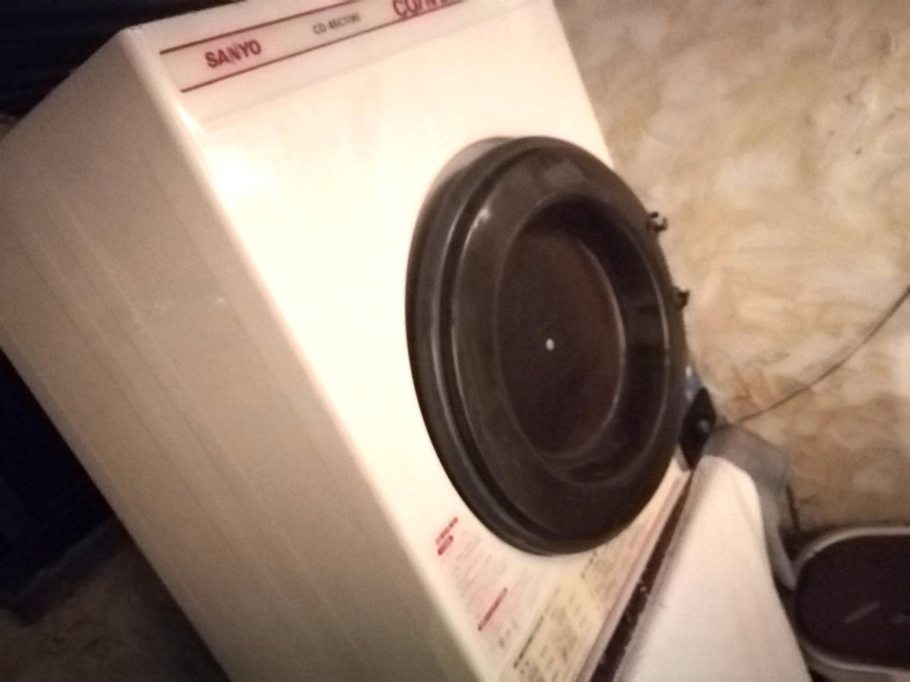 A white washing machine with a black door, placed on a tiled floor.