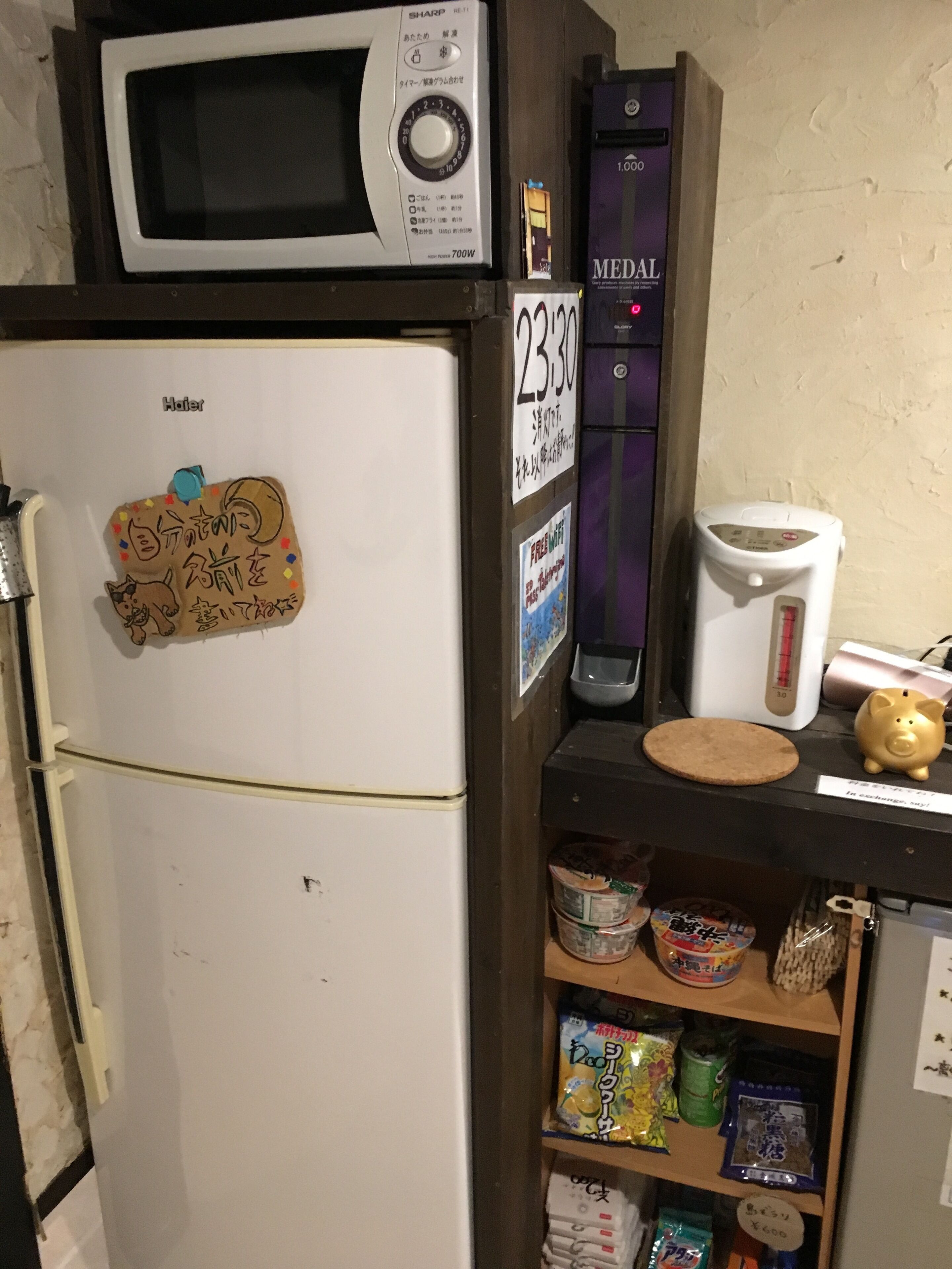 Una cocina con microondas, refrigerador y cafetera en la encimera.