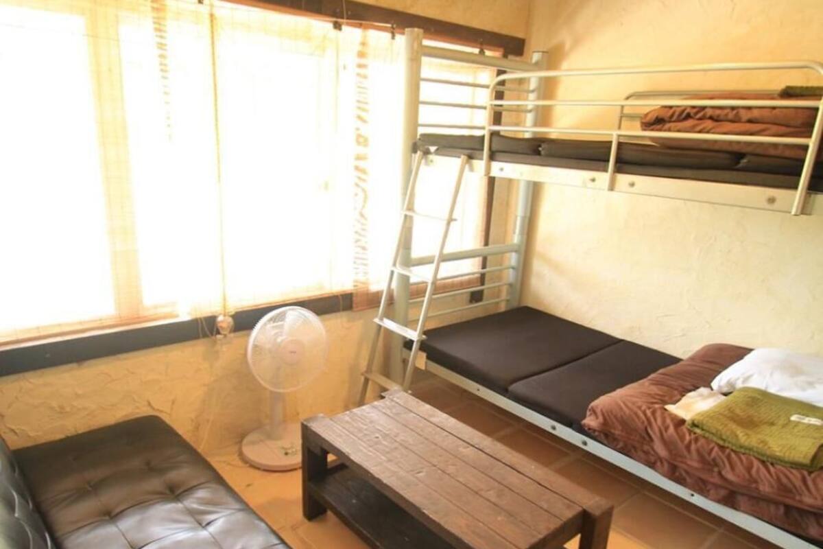 A room with a bunk bed, a leather sofa, and a small wooden table.