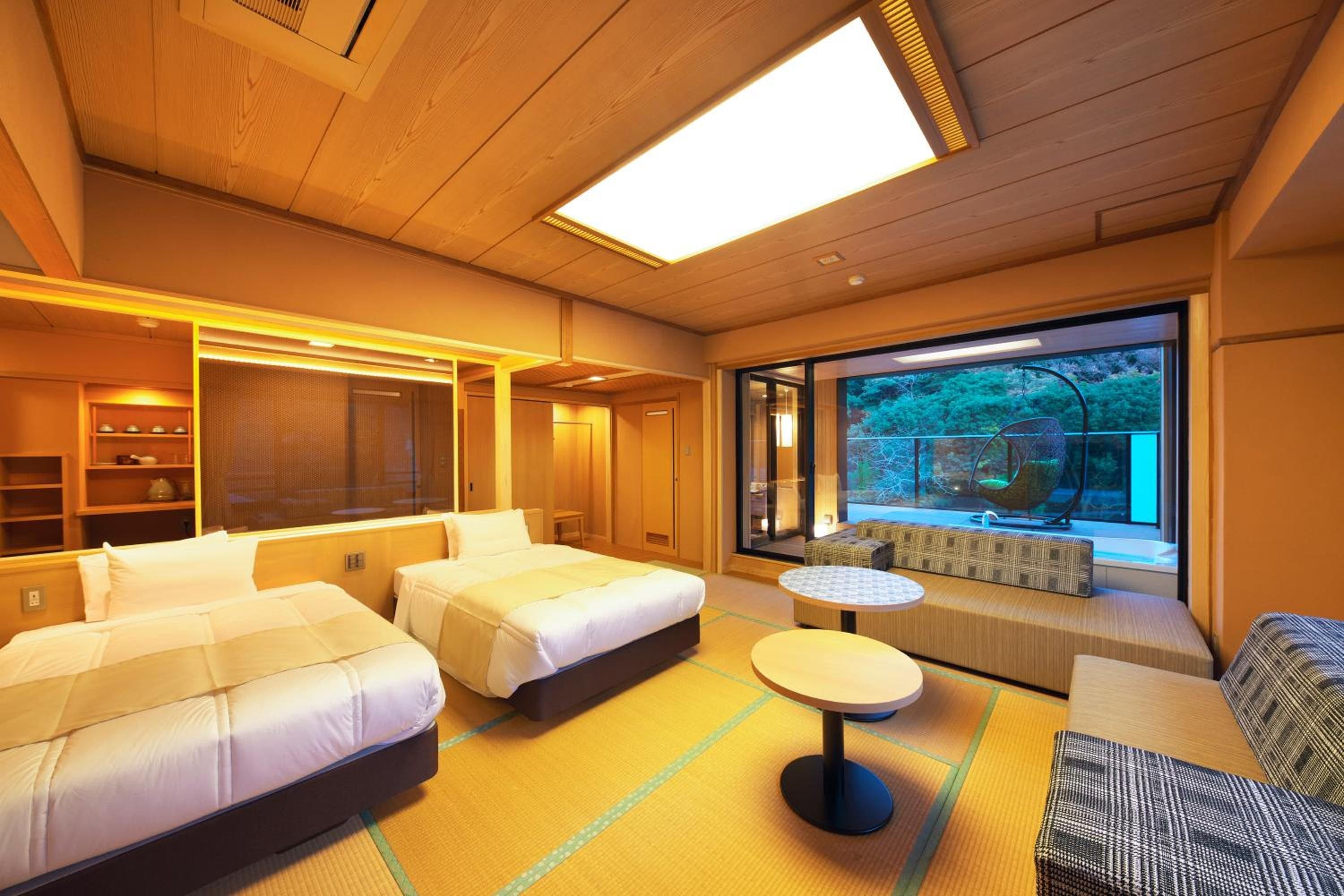 A hotel room with two beds, a seating area with a view, and a large window.