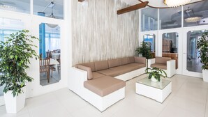 A modern living room with a sectional sofa, a coffee table, and potted plants.