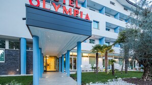 A modern hotel entrance with a sign reading "HOTEL OLYMPIA".