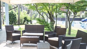 An outdoor seating area with wicker furniture and a large umbrella.