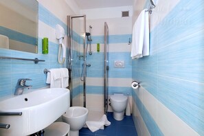 A bathroom with a glass-enclosed shower, a white sink, and a toilet.