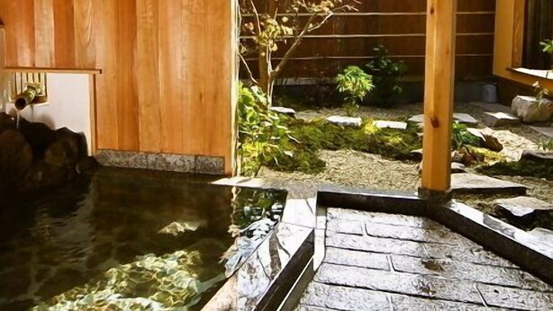 Een traditionele Japanse kamer met een houten interieur, een kleine binnentuin en een pad van stenen dat naar een vijver leidt.