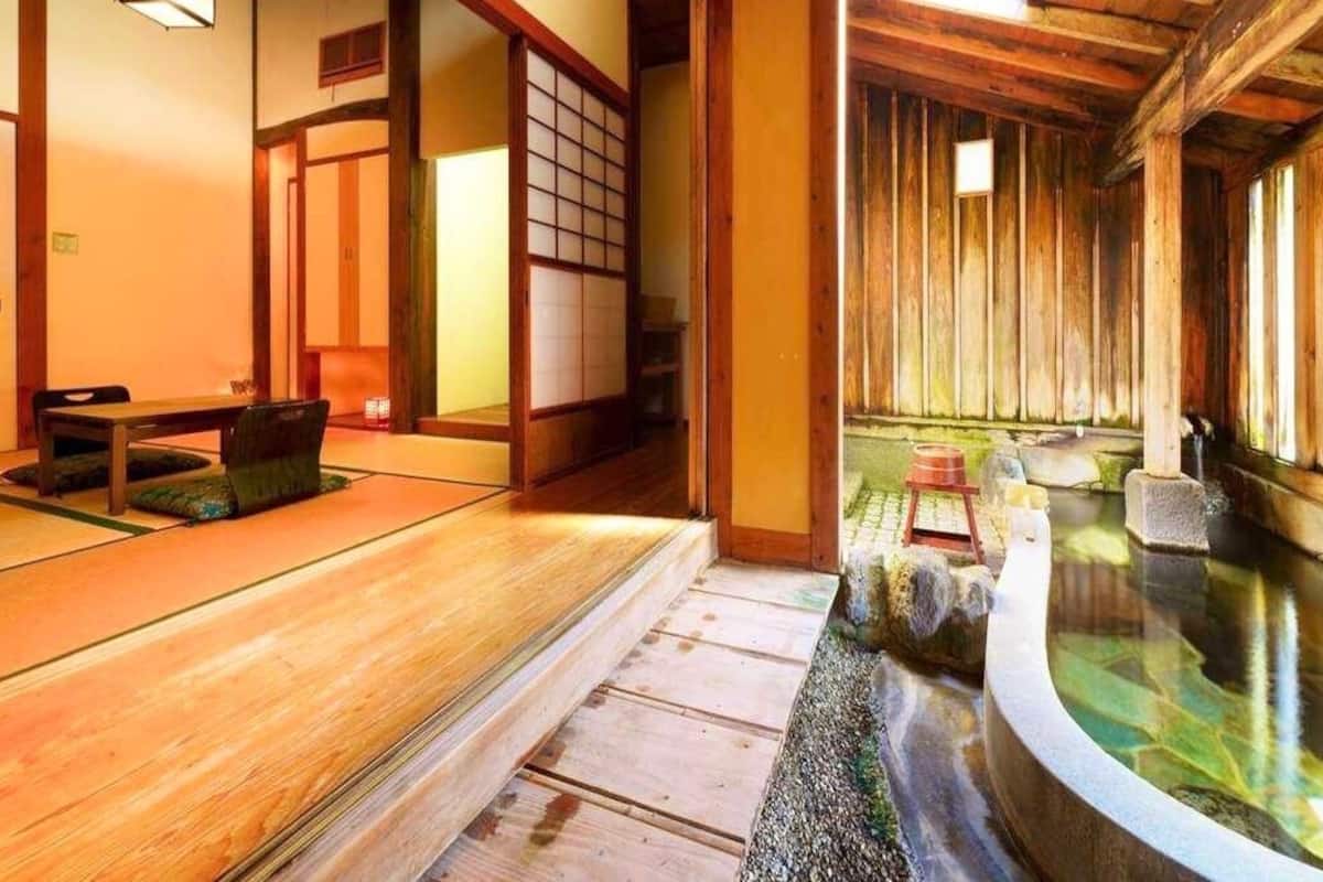 Une pièce de style japonais traditionnel, avec un sol recouvert de tatamis, un décor intérieur en bois et une petite fontaine d’intérieur.