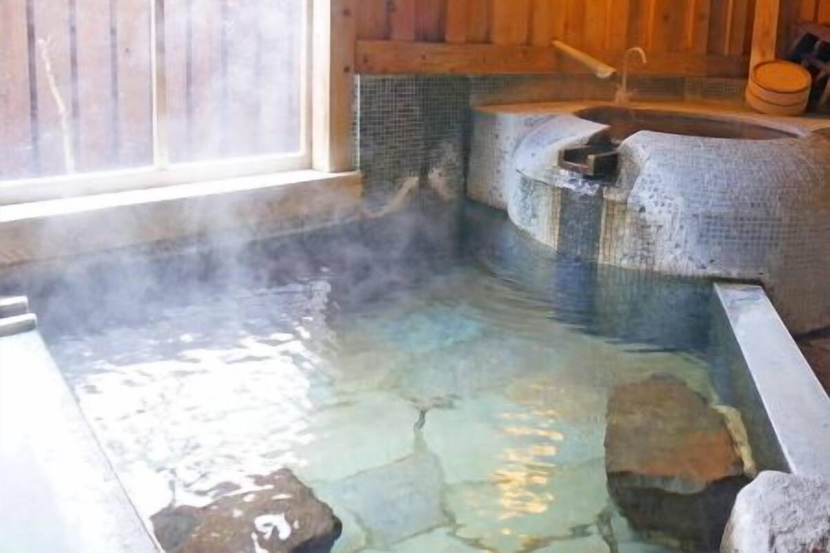 Un bain thermal avec des carreaux de pierre, des murs en bois et une fenêtre.