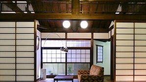 Een traditionele Japanse kamer met tatami vloerbedekking, een lage tafel met een vaas en een bank.
