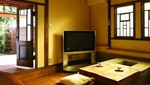 Een traditionele Japanse kamer met tatami vloerbedekking, een televisie en een lage tafel met kussens.