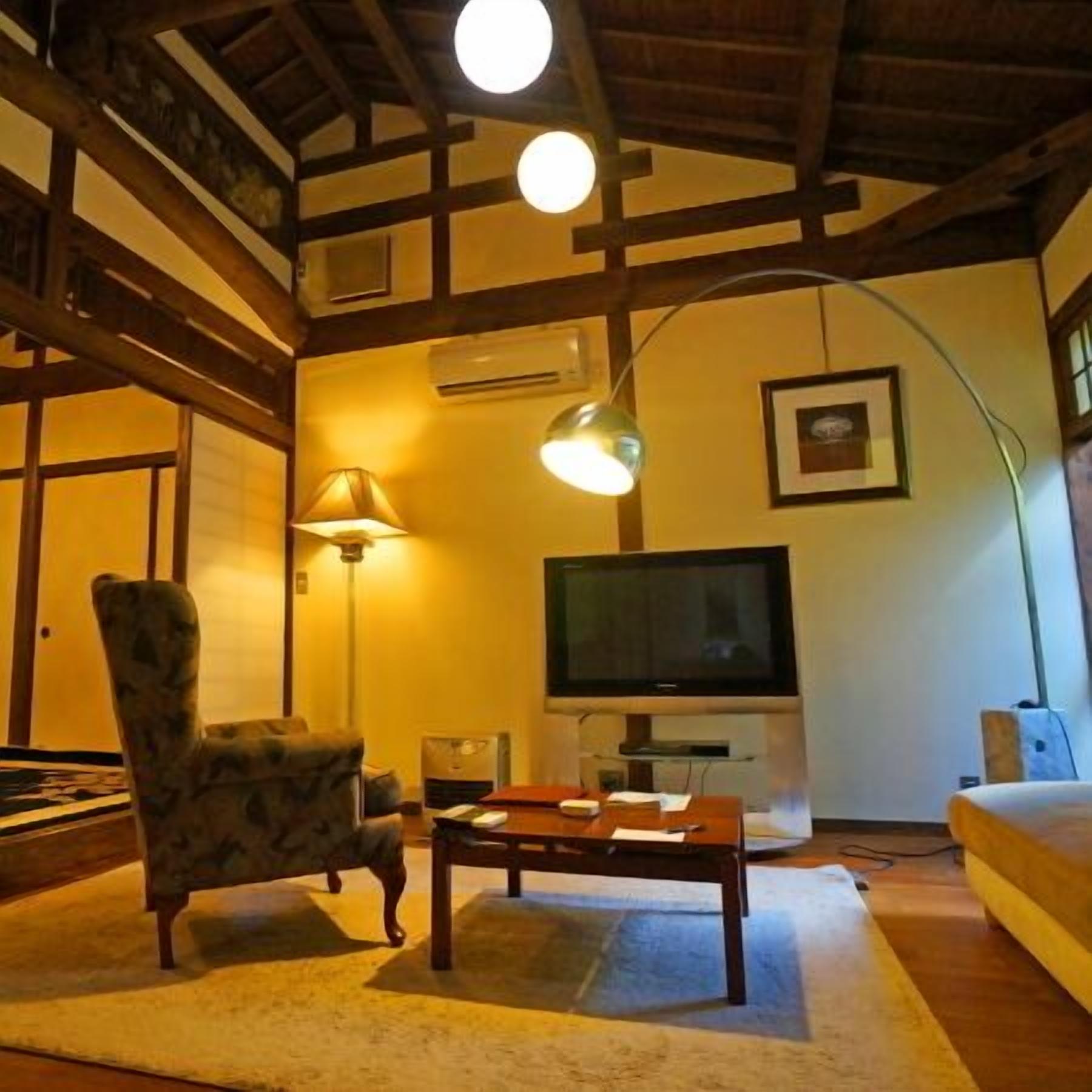 Una sala de estar con televisor, sofá, sillón y mesa.