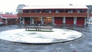 A building with a red facade, a covered outdoor area with a bench, and a circular driveway. - Canoe Safaris Lodge (Ohakune)