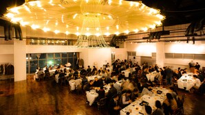 A large indoor dining area with multiple tables and chairs, a prominent chandelier, and large windows. - Hotel Zaaz (Oita)