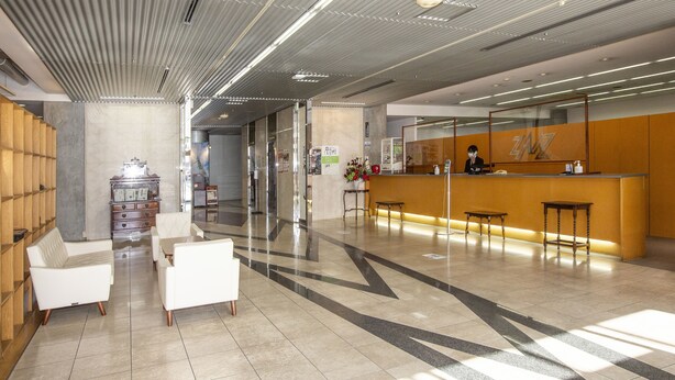 A modern lobby with a reception desk, seating area, and a staircase. - Hotel Zaaz (Oita)