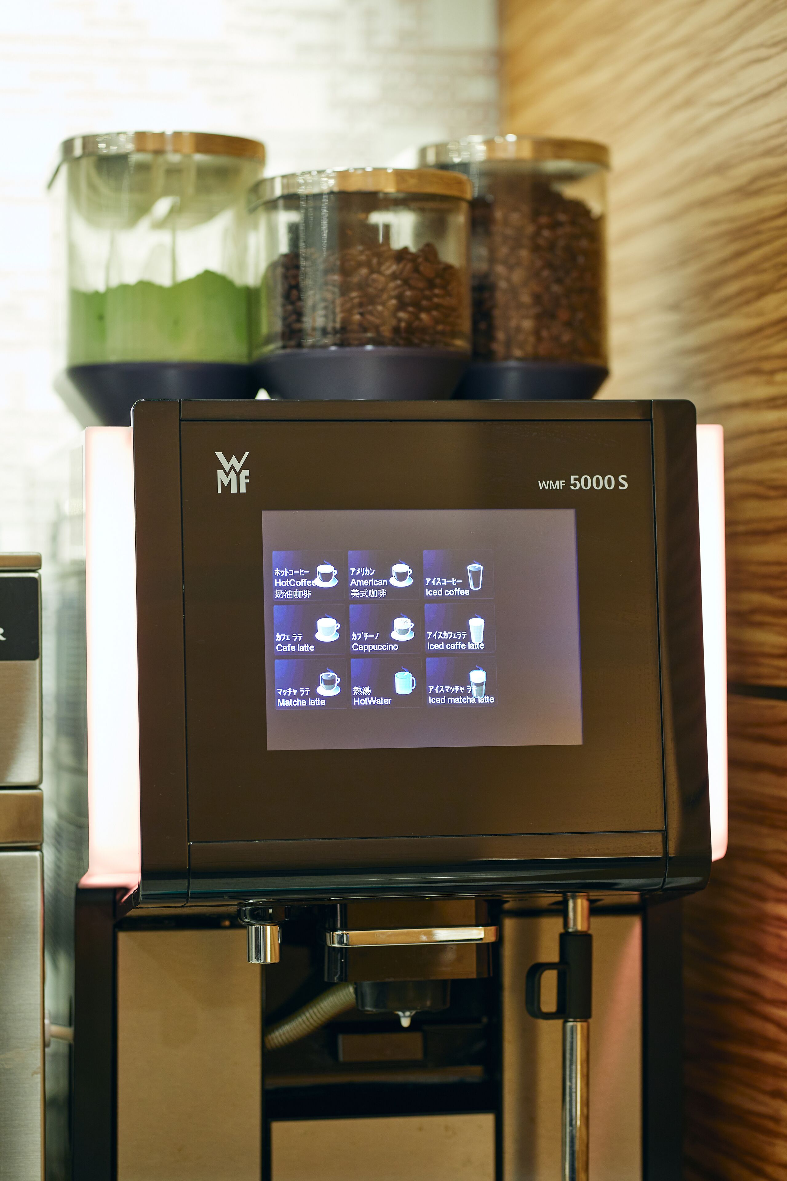 A coffee machine with a digital display menu, coffee beans, and a water container.