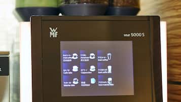 A coffee machine with a digital display menu, coffee beans, and a water container.
