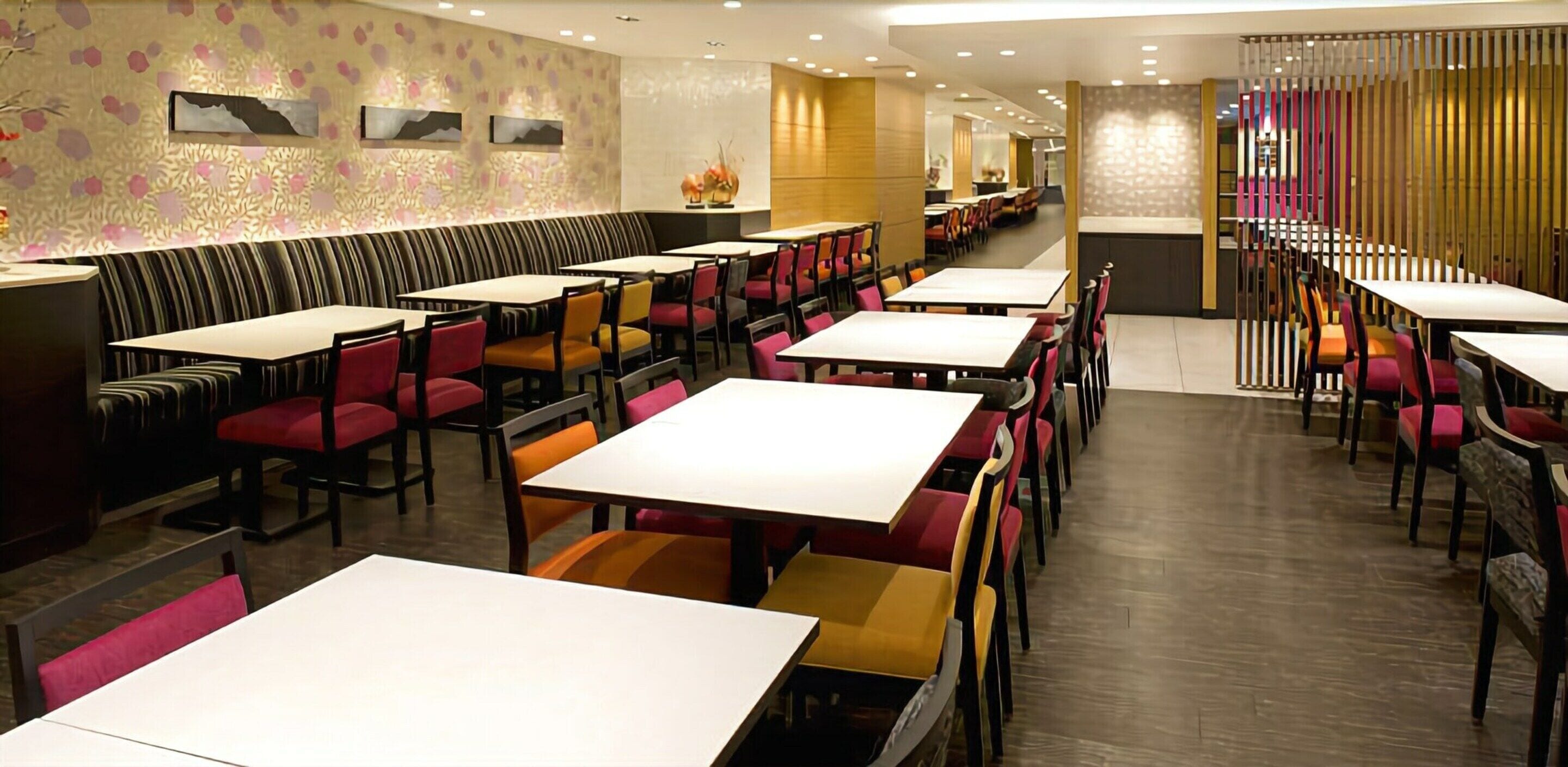Ein Restaurant mit mehreren Tischen und Sitzecken, das sich durch eine strukturierte Wand und Holzboden auszeichnet.