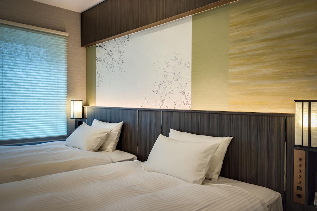 Quarto de hotel com duas camas, um mural grande na parede e design moderno.