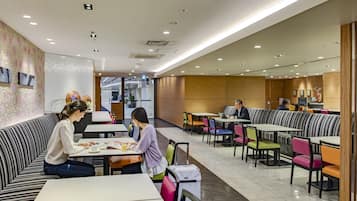 A modern dining area with booths and tables, a patterned wall, and a wooden accent wall.