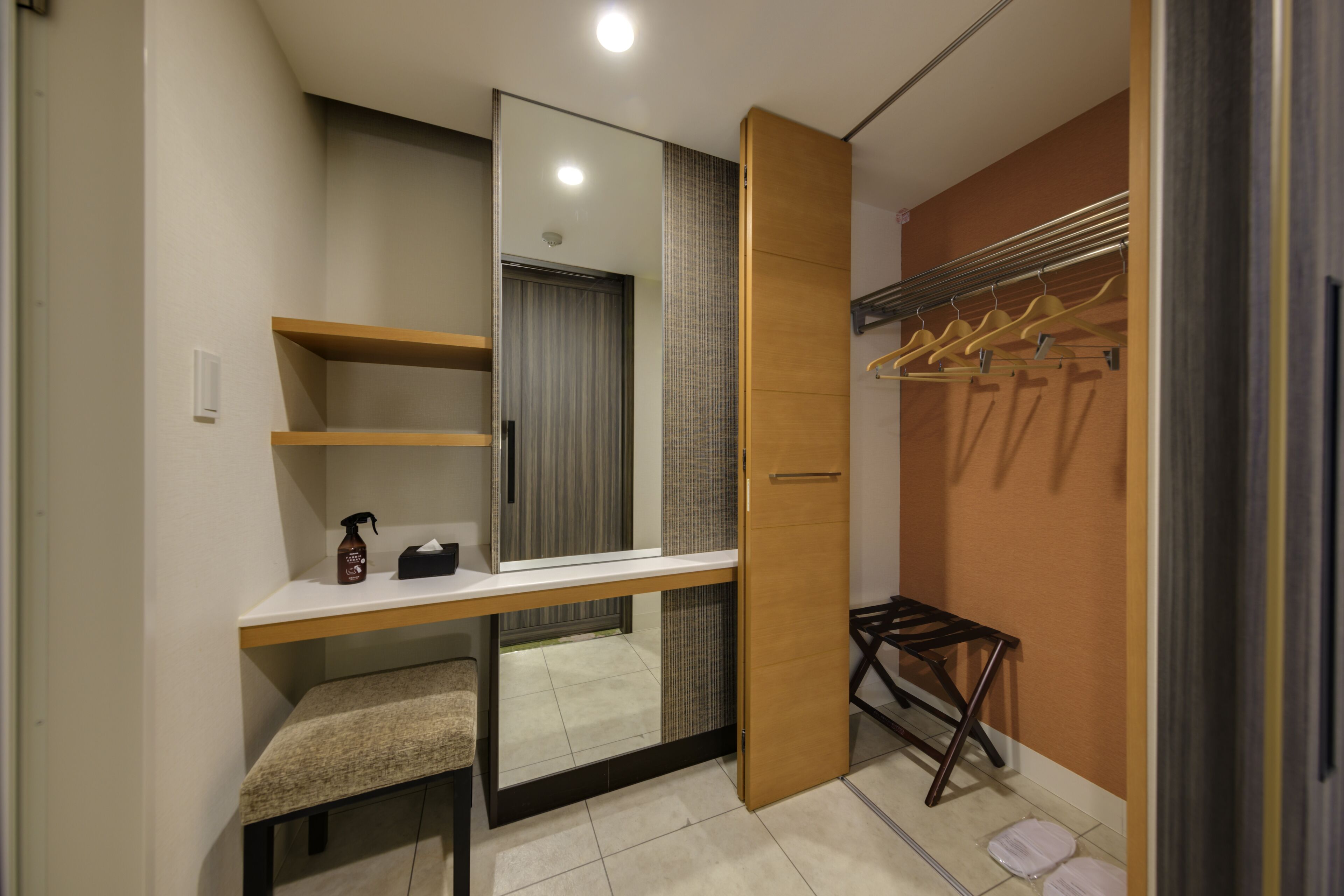 A modern bathroom with a vanity, mirror, towel rack, and a bench.