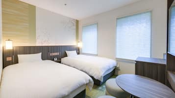 Une chambre d’hôtel avec deux lits, une petite table et un téléviseur fixé au mur.