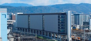 Un edificio moderno con fachada lineal, varios pisos y un tren pasando.