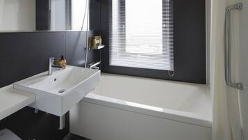 A modern bathroom with a white sink, mirror, and bathtub.